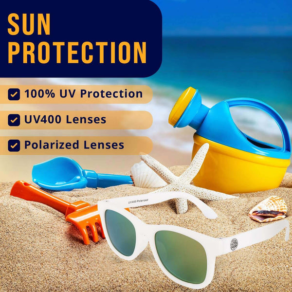 White polarized baby sunglasses with UV400 protection on a beach with toys, designed for kids aged 0-24 months.
